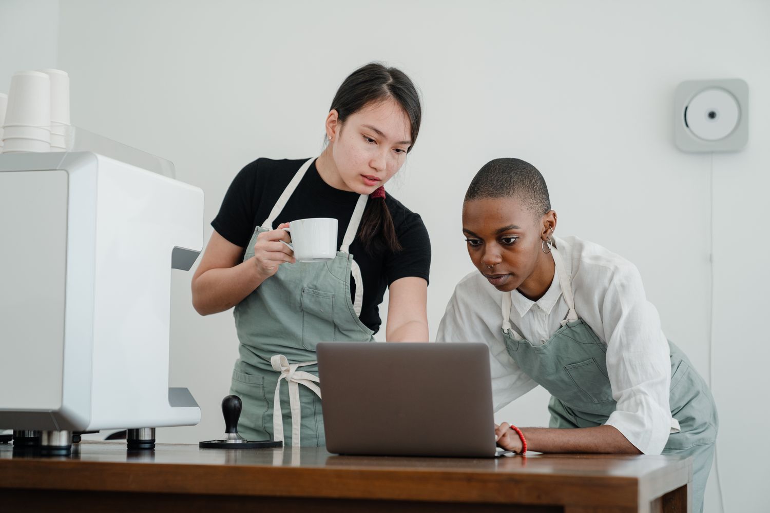 Two people in a small business working something out together on a laptop, one showing the other