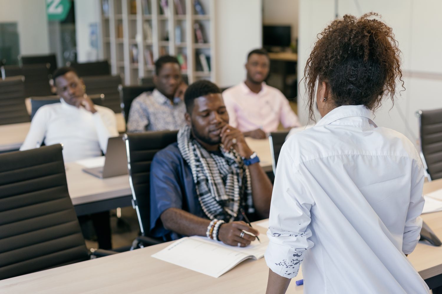 A small group working through a session together, taking notes while a facilitator talks them through it